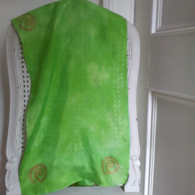 Lime green scarf with gold detail displayed on chair